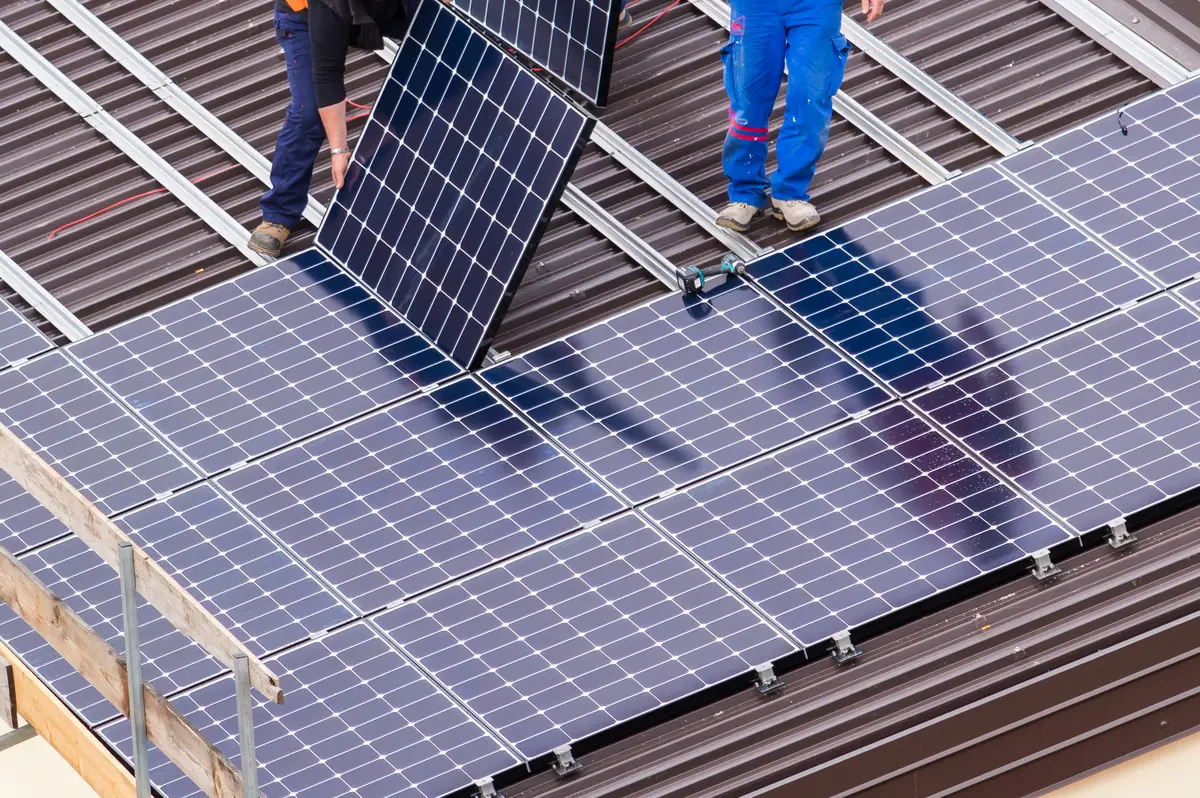 Instaladores montando paneles solares sobre un tejado de chapa en Úbeda
