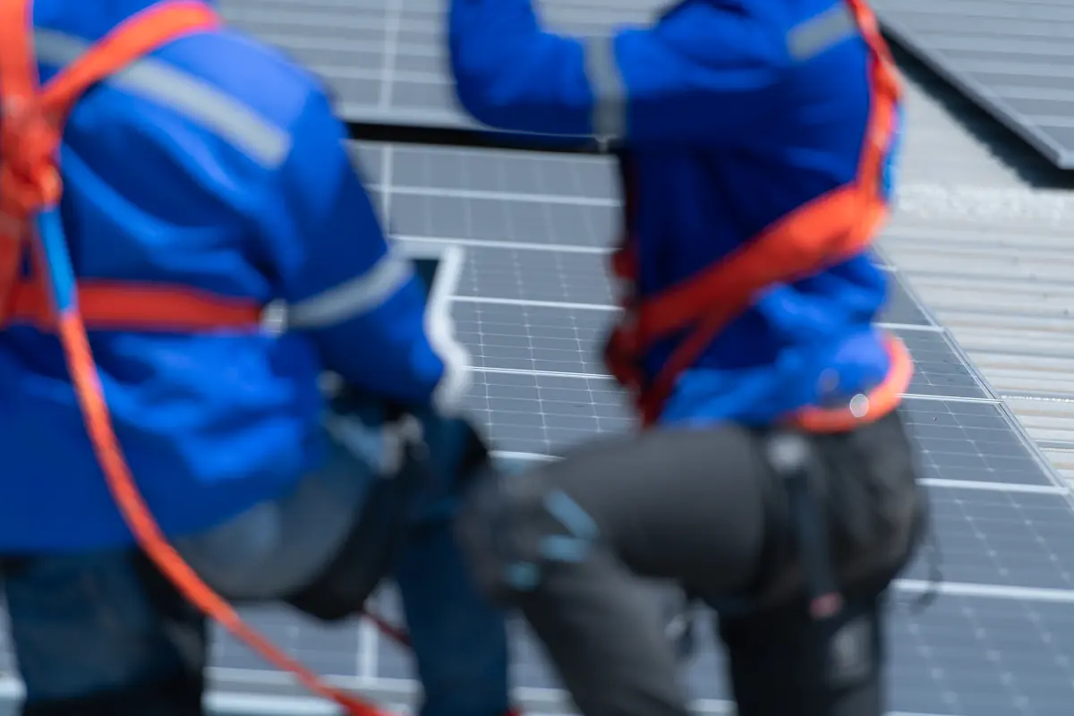 Instaladores con equipo de seguridad trabajando en una cubierta con paneles solares en Úbeda