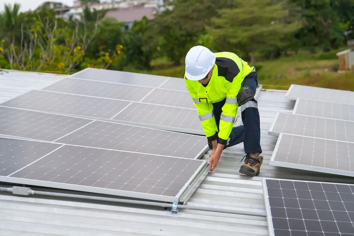 Instalador con casco ajustando un panel solar en la estructura de una cubierta de Úbeda